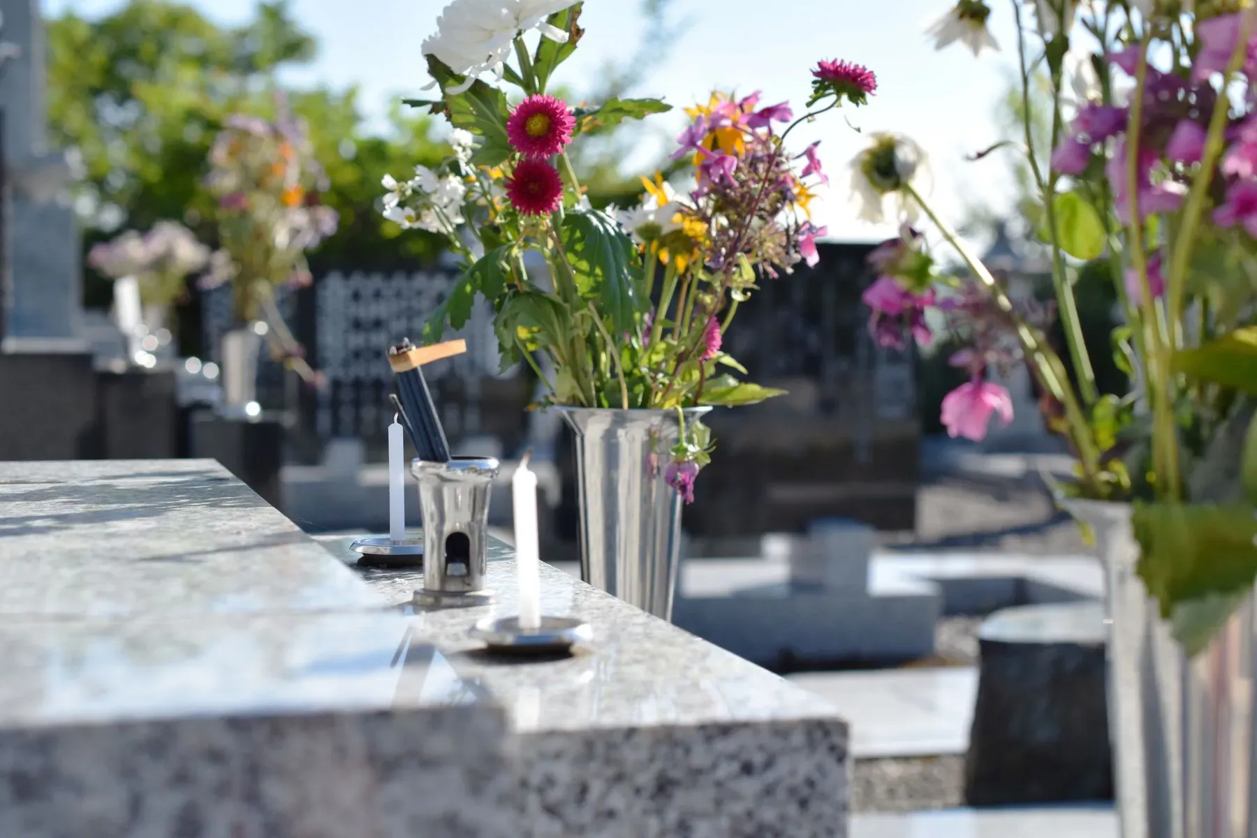Vase de fleurs et bougies déposés sur une pierre tombale pour le souvenir.