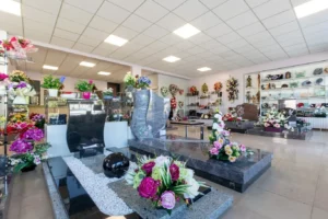 Exposition de monuments funéraires en granit et compositions florales de deuil.