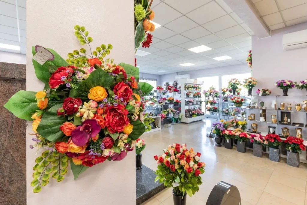 Arrangement de fleurs de deuil artificielles et plaques commémoratives en boutique.