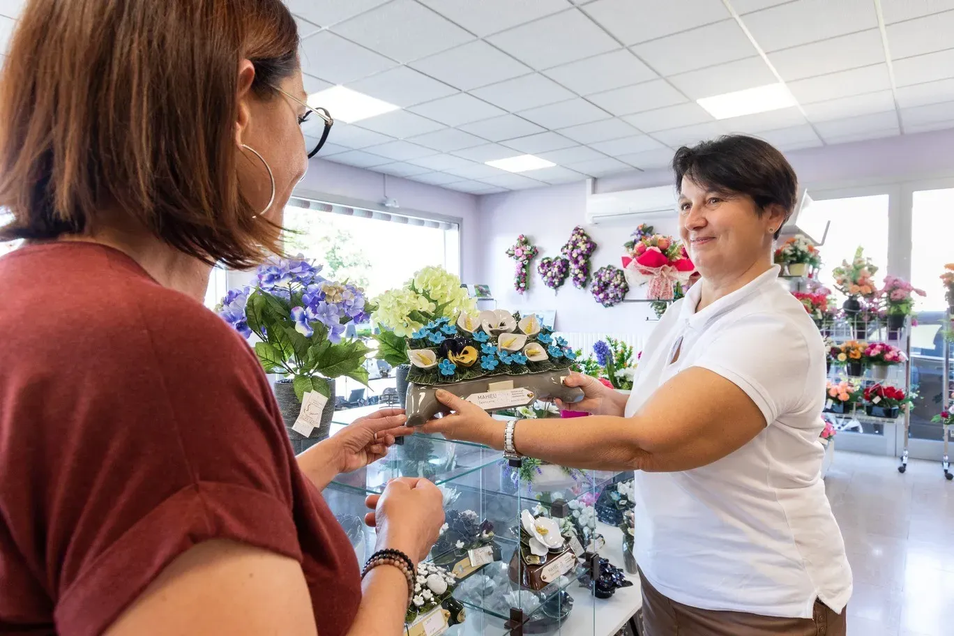 Conseillère funéraire présentant une plaque commémorative en céramique à une cliente.